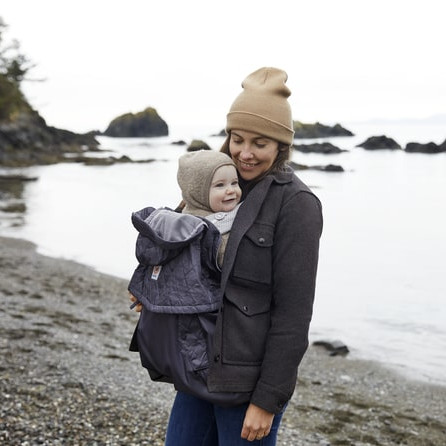 Women carrying baby with all weather cover nearby the sea