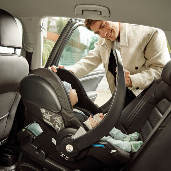 father putting baby with the car seat into the car